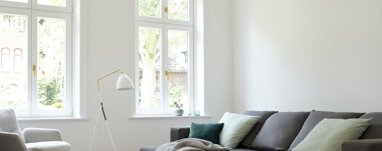 Helles, modernes Wohnimer mit grau-braunem Sofa vor einer weißen Wand. Helles, modernes Wohnimer mit grau-braunem Sofa vor einer weißen Wand.